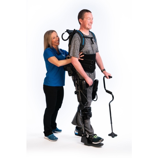 Ekso NR – egzoszkielet rehabilitacyjny, pacjent chodzący z pomocą terapeuty i laski.