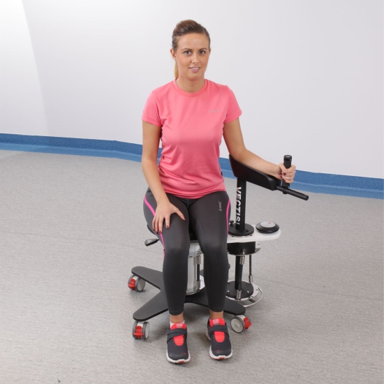 Vectis Mini – urządzenie do rehabilitacji stawu ramiennego, pacjentka podczas ćwiczeń siedzących.