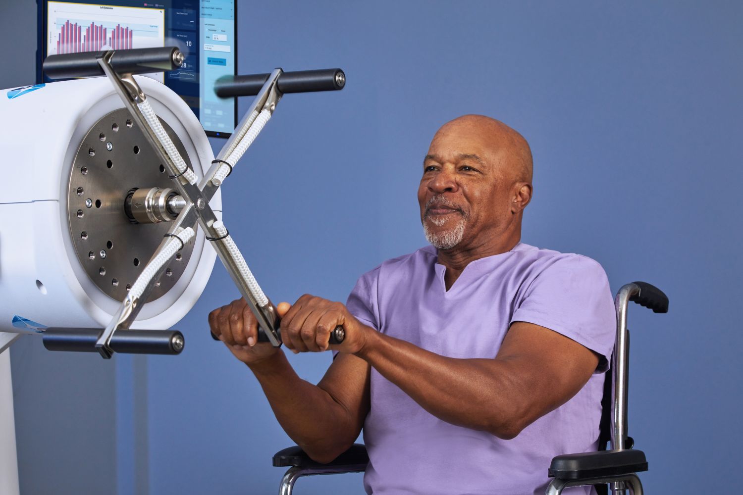 Saffire – trening kończyn górnych u osoby poruszającej się na wózku inwalidzkim z kontrolą parametrów na ekranie.